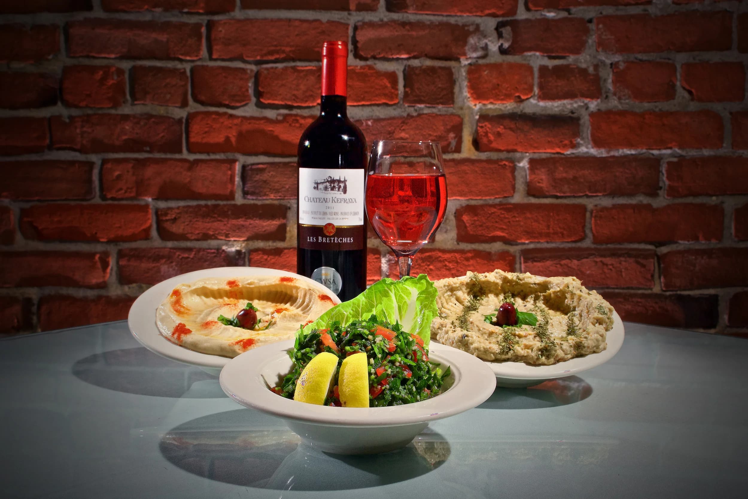 Lebanese mezze at Al-Amir Portland — hummus, tabooli and baba ghannooj with Lebanese wine against the restaurant's brick wall